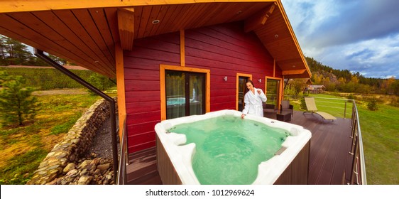 The hot tub is on the terrace of the cottage. The girl is checking the water in the Jacuzzi. Cottage with hydromassage bath. Jacuzzi in the street. Jacuzzi with a girl.