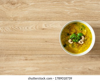 Hot Vegan Yellow Curry Soup With Healthy Vegetables And Green Salad In A White Bowl Top Down Photo With Bright Wooden Texture Background Top Down View