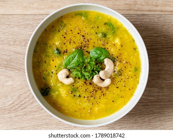 Hot Vegan Yellow Curry Soup With Healthy Vegetables And Green Salad In A White Bowl Top Down Photo With Bright Wooden Texture Background Top Down View