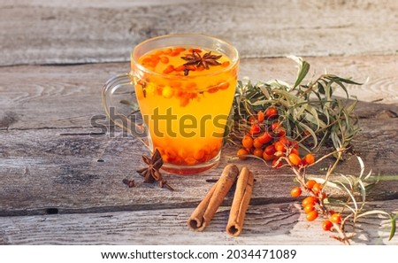 Hot vitamin Sea buckthorn tea into a cup, stands on an old woodenbackground. Relaxation and herbal medicine, anti-cold drink, flu season