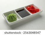 Hot wasabi paste, soy sauce and ginger on white table, closeup