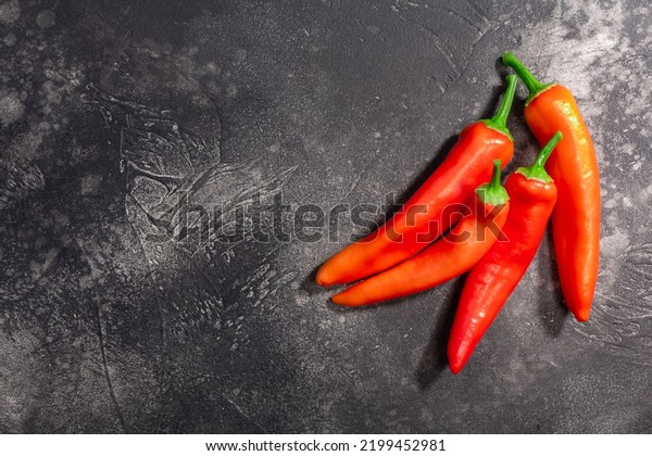 Hot wax chile peppers atop dark textured backdrop,\
top view, copy space. Capsicum annum fruits, Gabi variety.\
Hungarian paparika chilis