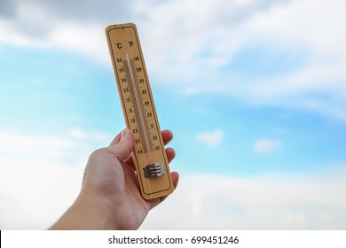 Hot Weather Concept, Hand Hold Thermometer And Blue Sky