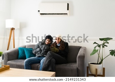 Hot weather outside. Young couple feeling very cold after turning on the air conditioning in their home