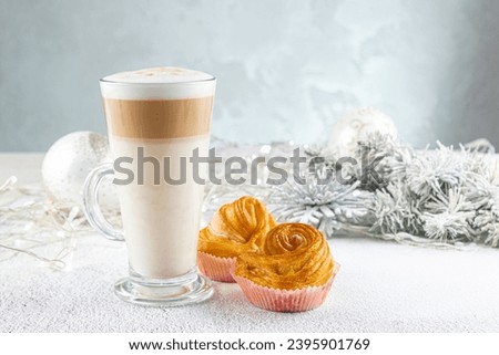 Hot winter drink on a festive Christmas table. layered latte coffee with delicious buns. Cozy home atmosphere.
 Christmas decorations, concept  Holiday. Selective focus, copy space for text
