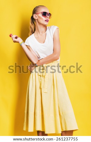 hot woman in yellow skirt with lollipop on yellow background