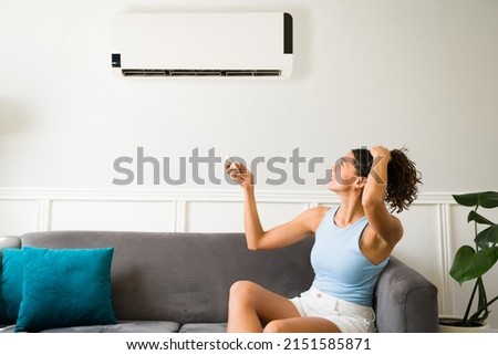 Hot young woman feeling sweaty during a heat wave because her air conditioning is not working 