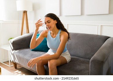 Hot young woman without an ac unit or fan putting an ice cold drink in her forehead to cool down during a heat wave
