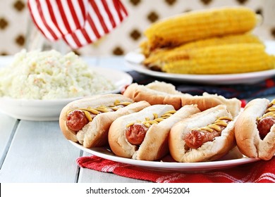 Hotdogs with Mustard, cole slaw and corn on a cob at a 4th of July BBQ picnic. Extreme shallow depth of field.