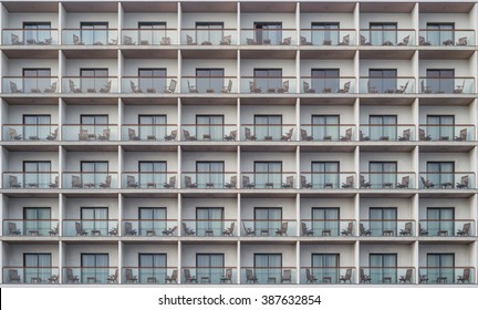 Hotel apartment balcony texture pattern. Detail of the facade of a apartment building, outdoor view of rows of balconies / terrace / gallery always equipped with small table and two chairs / seats.