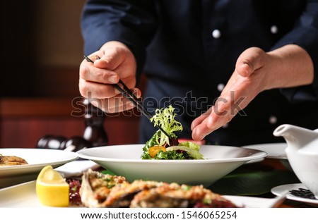 a hotel chef. He is decorating his food.