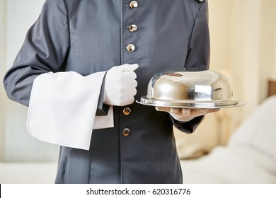 Hotel Clerk Serving Food With Cloche In A Hotel Room