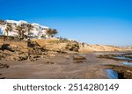 Hotel complex on cliff at La Source beach in Taghazout near Agadir, Morocco. Rugged rocky coastline of Atlantic ocean attracts surfers and tourists. Famous surf spot.