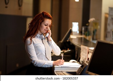 Hotel Concierge .Reception Of Hotel, Desk Clerk, Woman Taking A Call And Smiling.