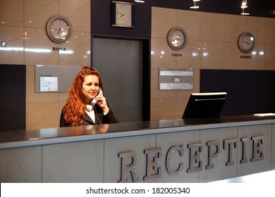 Hotel Concierge .Reception Of Hotel, Desk Clerk, Woman Taking A Call And Smiling.