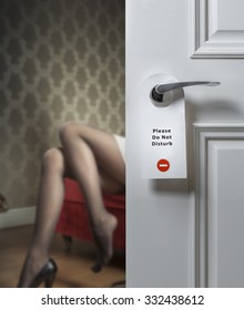 Hotel door with do not disturb icon and sexy female legs on the background; adultery concept