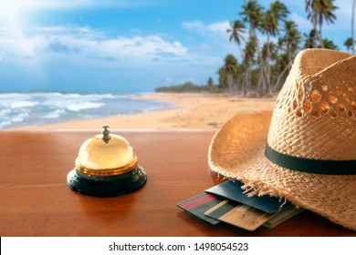 Hotel Lobby Against The Backdrop Of A Tropical Beach. Chekin. Straw Hat, Passport, Bank Cards.