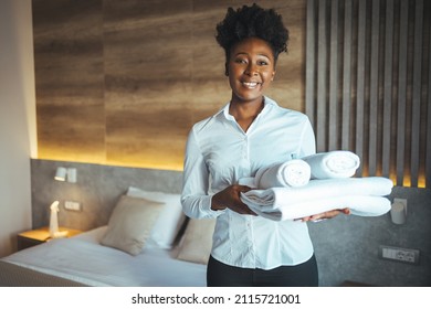 Hotel maid bringing fresh towels to the room. Maid clean the room and replace the bedsheets and towels. Maid with fresh towels in hotel room - Shutterstock ID 2115721001