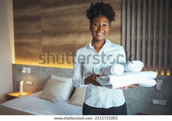 Hotel maid bringing fresh towels to the room. Maid\
clean the room and replace the bedsheets and towels. Maid with\
fresh towels in hotel\
room