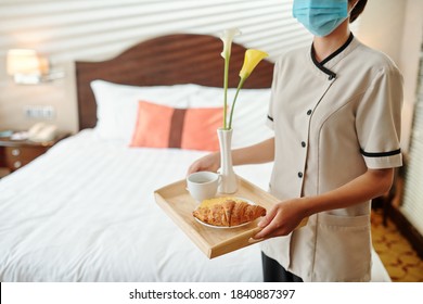 Hotel Maid Wearing Medical Mask When Bringing Tray With Breakfast And Flowers In Hotel Room