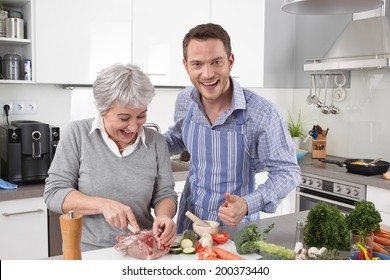 Hotel Mama: Young Man And Older Woman Cooking Together Roast Pork.