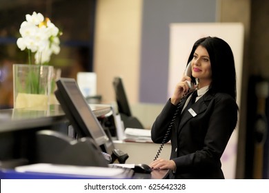 Hotel Receptionist. Modern Luxury Hotel Reception Counter Desk With Bell. Happy Female Receptionist Worker Standing At Hotel Counter.