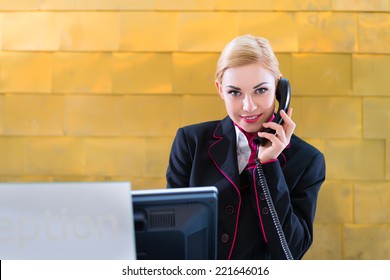 Hotel Receptionist With Phone On Front Desk