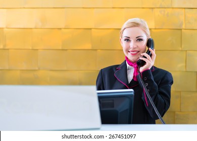 Hotel Receptionist With Phone On Front Desk