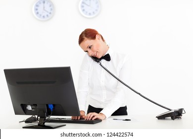 Hotel Receptionist Talking On Phone While Checking On Computer