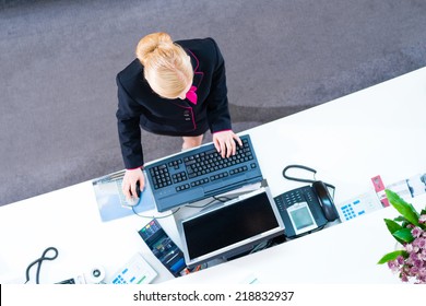 Hotel Receptionist Working On Computer At Front Desk Office 