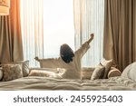 Hotel relaxation on lazy day with Asian woman waking up from good sleep on bed in weekend morning resting in comfort bedroom looking toward city view, having happy, work-life quality balance lifestyle