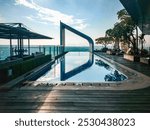 Hotel rooftop swimming pool design. Hotel rooftop swimming pool is decorated with deck chairs, green plants, trees, and a city view from the top.