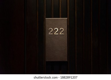 Hotel Room With 222 Number, Dark Wood Door, Black Number Plate With Golder Numbers