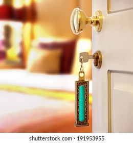 Hotel Room Or Apartment Doorway With Key And Keyring Key Fob In Open Door And Bedroom In Background