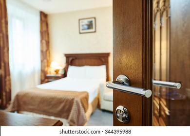Hotel room or apartment doorway with open door and bedroom in background