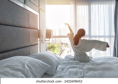 Hotel room comfort with good sleep easy relaxation lifestyle of Asian girl on bed have a nice day morning waking up, taking some rest, lazily relaxing in guest bedroom in city hotel 