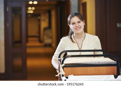 Hotel Room Service. Female Housekeeping Worker With Bedclothes Linen In Cart