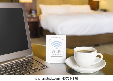 Hotel room with wifi access sign, laptop and cup of coffee