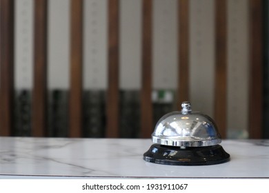 Hotelservice-Glocke auf weißem Tischglas und Simulationshotel-Hintergrund. Konzept Hotel, Reisen, Zimmer, Ein Service-Glocke im Hotel