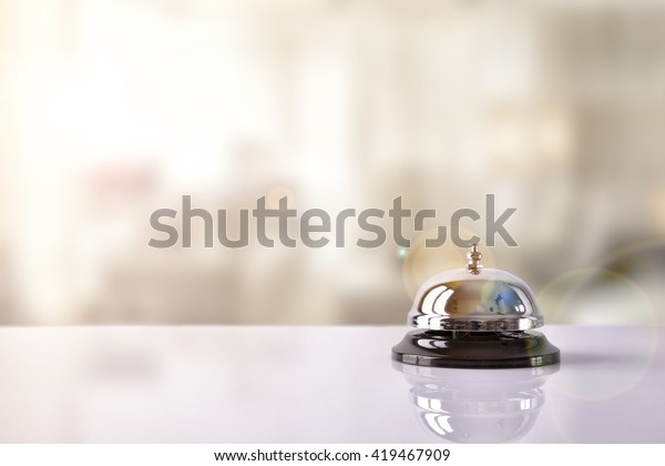 Hotel service\
bell on a table white glass and simulation hotel background.\
Concept hotel, travel,\
room