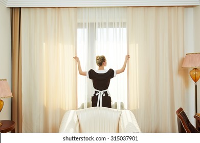 Hotel service. female housekeeping chambermaid worker with opening curtains of window in room - Shutterstock ID 315037901