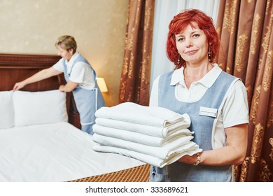 Hotel Service. Female Housekeeping Staff Worker With Towels In Front Of Maid Making Bed In Room