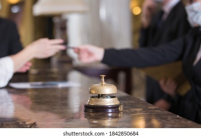 the hotel staff serves guests in medical masks - Shutterstock ID 1842850684