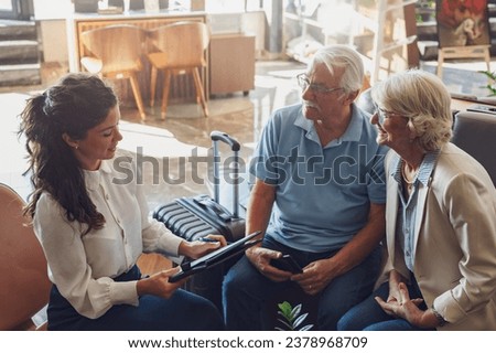 A hotel or travel agency representative is talking with a senior tourist couple offering various tourist services