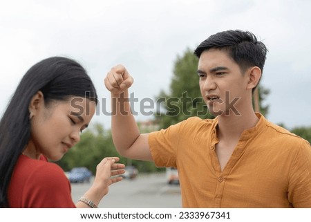 A hotheaded and angry young asian man curses and swears at his girlfriend while at the parking lot. An emotionally abusive boyfriend. Stock photo © 