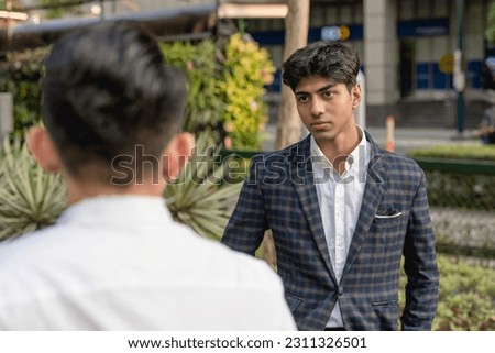 A hotheaded young indian man stares down his workmate while outside the office. Animosity in the workplace. Stock photo © 