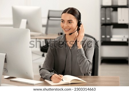 Hotline operator with headset and notebook working in office