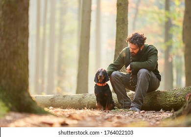 Hound as a hunting dog together with a hunter or forester take a break in the forest