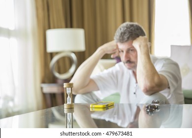 Hour clock counting the time while middle aged man looking at his phone longingly
