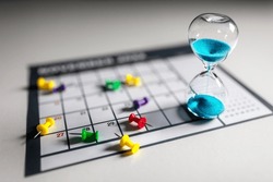 Hour Glass On Calendar With Thumbtacks Concept For Time Slipping Away For Important Appointment Date, Schedule And Deadline